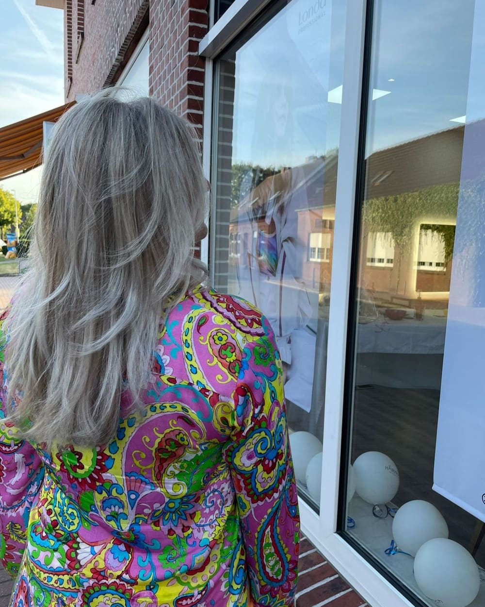 Graues, gestuftes Haar von hinten vor dem Schaufenster