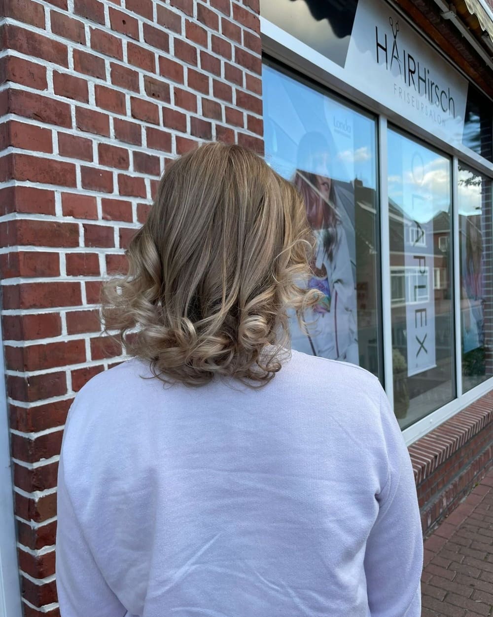 Aschblonde Locken vor der Klinkerwand